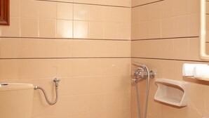 Et lille badeværelse med toilet, håndvask og bruser.