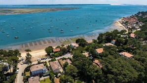 An aerial view of a coastal town with numerous boats in the water, a beach, and residential buildings. - Villa des Sables: Cosy Apartment with Bassin View and Balcony (Lège-Cap-Ferret)