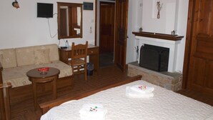 Ein Zimmer mit einem Bett, einem Holztisch, einem Sessel, einer Couch, einem Kamin und einem Fernseher.