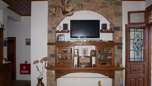 Ein Wohnzimmer mit einem Kamin aus Stein, einem darüber montierten Fernseher und einem Holzschrank darunter.