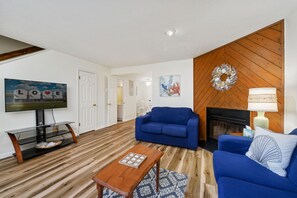 Relax in this stylish living room with a sofa, coffee table, and flat-screen TV, plus a fireplace and wall art.