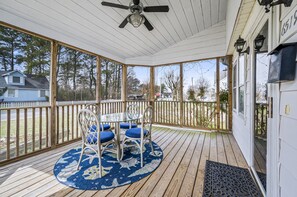 A covered porch with a table and chairs, a ceiling fan, and a view of a residential area. - Starbright Cottage by Seaside Vacations & Sales (Chincoteague)