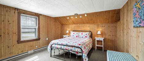 Un dormitorio acogedor con una cama, mesitas de noche, un banco y una ventana.