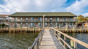 Ein Motel am Wasser mit einem hölzernen Steg, der zu einem Gebäude mit mehreren Balkonen führt.