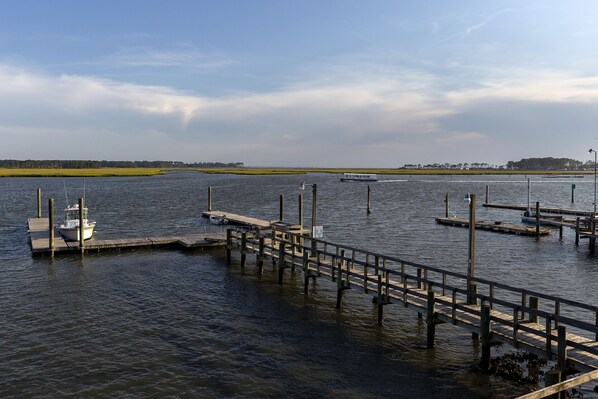 Een jachthaven met houten steigers die zich uitstrekken over kalm water, een klein bootje aan de pier afgemeerd en een veerboot in de verte.