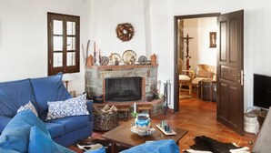 A living room with a fireplace, blue sofas, a coffee table, and a cowhide rug. - Maria s Cozy Loft in Makrinitsa (Volos)