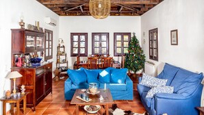 A cozy living room with a blue sofa, a wooden coffee table, a Christmas tree, and a rustic fireplace. - Maria s Cozy Loft in Makrinitsa (Volos)