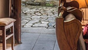 A doorway leading to a stone wall and greenery, with a wooden chair and a lamp in the foreground. - Calliope s Stone Manor (Zagora-Mouresi)