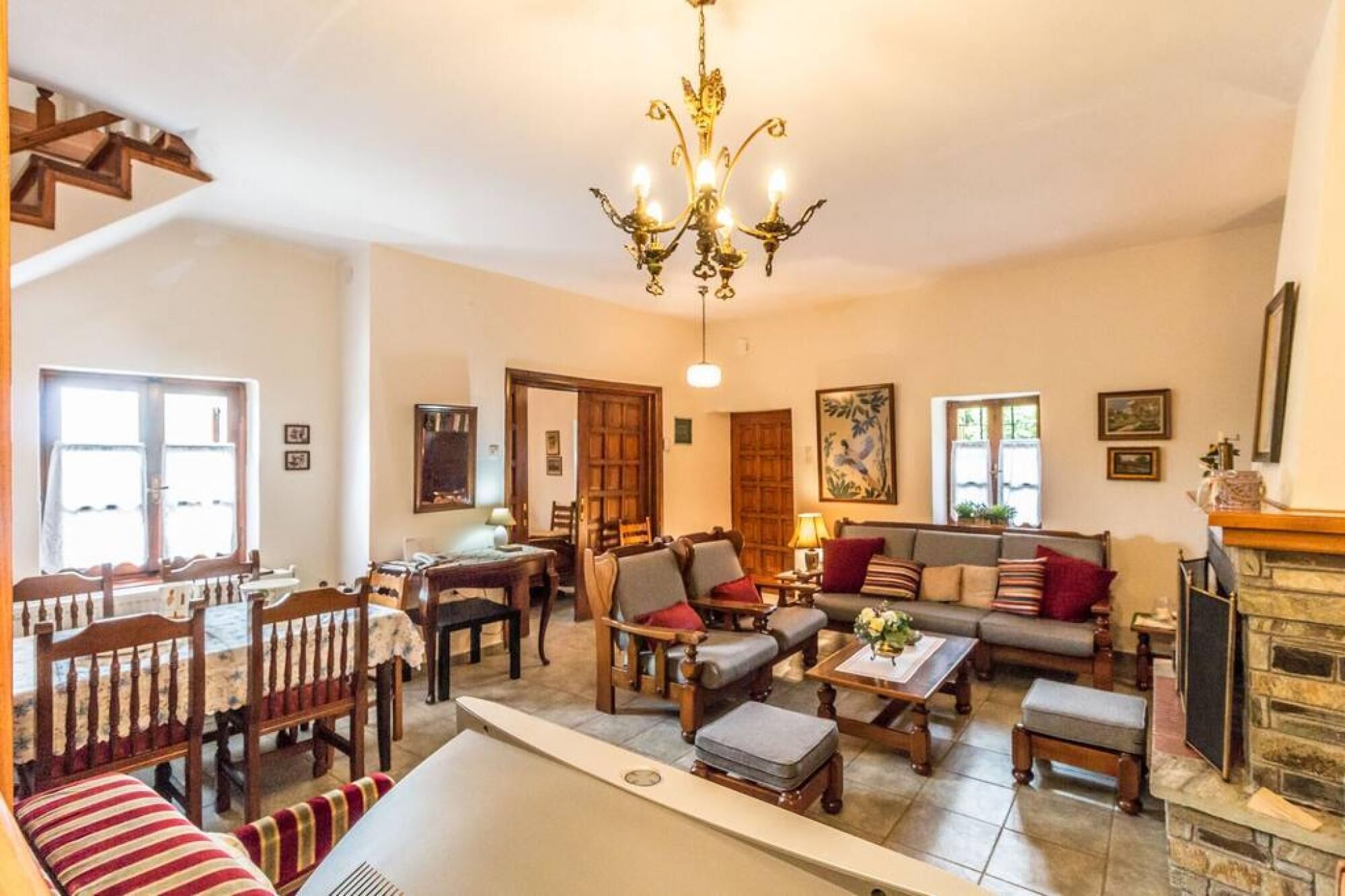 A spacious living room with a fireplace, a dining area with wooden furniture, and a staircase leading to an upper level.