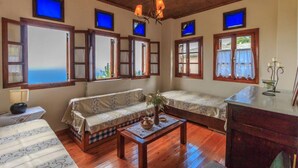 A cozy room with wooden floors, a sofa, a small table with a vase, and a desk with a lamp. - Calliope s Stone Manor (Zagora-Mouresi)
