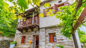 A two-story stone building with a balcony, stone walls, and wooden shutters. - Calliope s Stone Manor (Zagora-Mouresi)