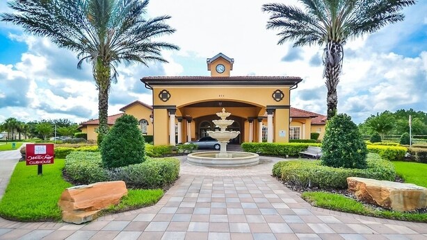 A hotel entrance with a fountain, palm trees, and a sign for the Yachts Clubhouse.