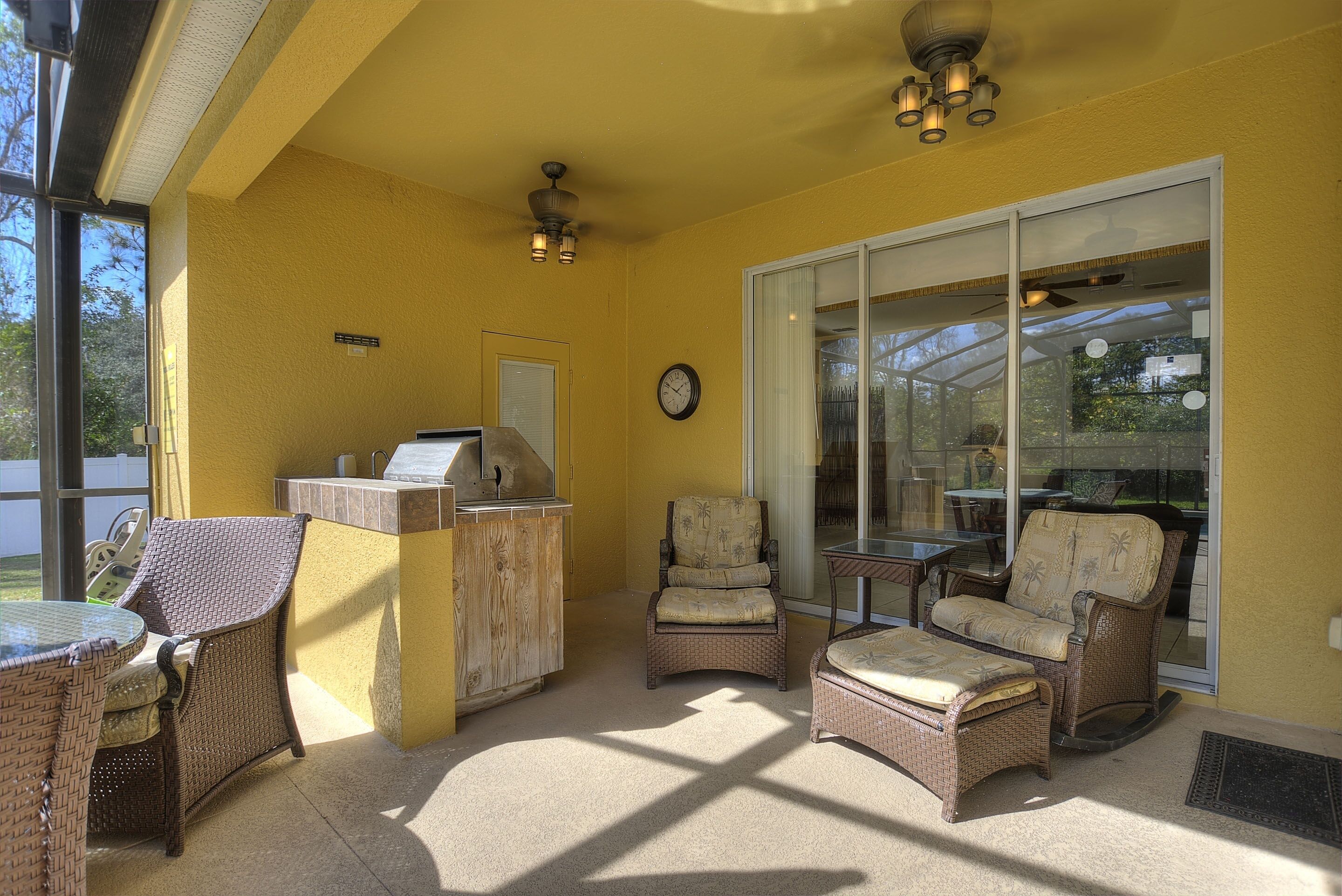 A patio area with wicker furniture, a grill, and a sliding glass door leading to a covered outdoor space.