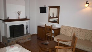 Une pièce avec une cheminée, un canapé, une table à manger avec des chaises et un téléviseur fixé au mur.