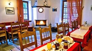 Un coin repas avec des chaises et des tables en bois, une cheminée et un tapis à rayures.