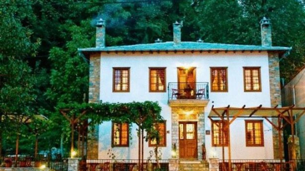 Un bâtiment en pierre de deux étages, doté d’un balcon et d’un porche couvert.