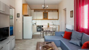 A compact living space with a kitchenette, a dining area, and a seating area with a sofa and a coffee table. - Aethra House in Agria Volou (Volos)