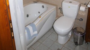 Een badkamer met een bad, toilet en een prullenbak.