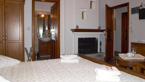 Een hotelkamer met een groot bed, een open haard, een spiegel en houten meubels.
