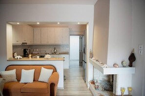 A modern kitchen with light wood cabinets, a central island, and a built-in oven. - Betty s 4 Seasons in Agria (Volos)
