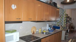 A kitchen with wooden cabinets, a microwave, stove, and a sink.
