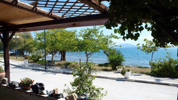 A coastal view with a pergola, potted plants, and a stone wall.