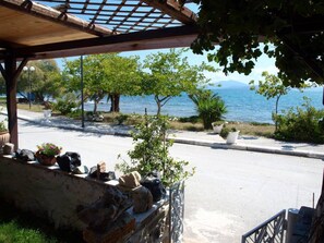 Ein Küstenblick mit einer Pergola, Kübelpflanzen und einer Steinmauer.