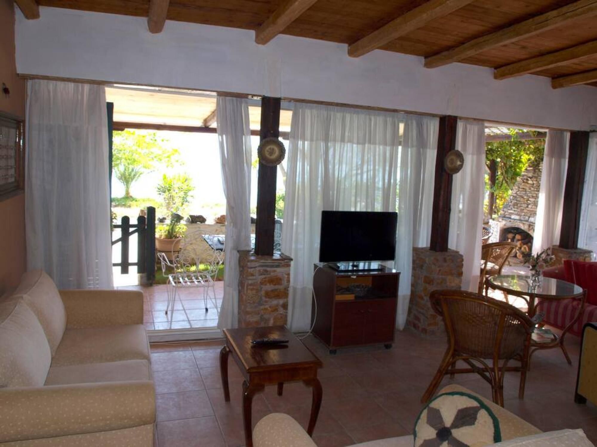 A living room with a sofa, TV, and dining area with chairs and a table.