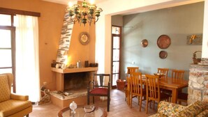 A living room with a fireplace, a sofa, a dining table with chairs, and a chandelier.