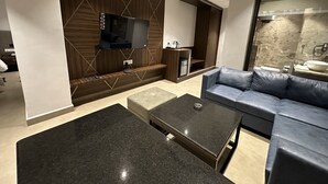 Una sala de estar moderna con una televisión de pantalla plana montada en una pared de madera, un sofá gris y una mesa de centro.