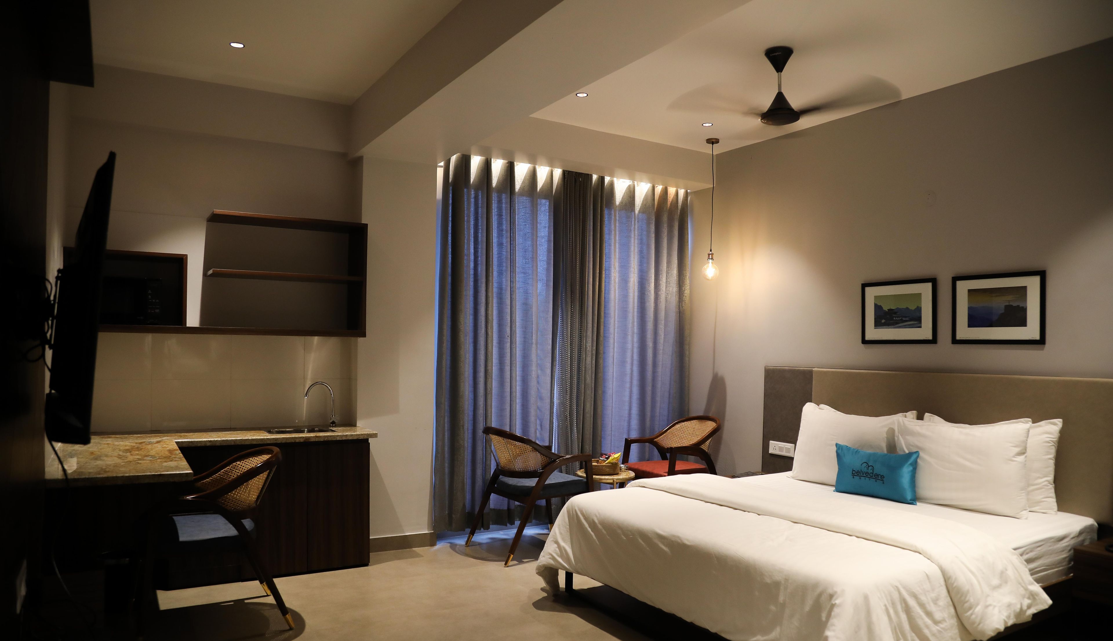 A hotel room with a bed, a desk, a chair, a television, and a ceiling fan.