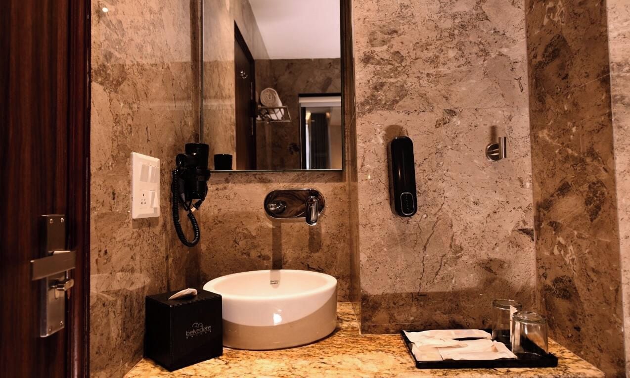 A bathroom with a marble sink, a mirror, a telephone, and a bottle of hand soap.