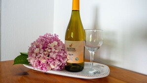 A bottle of Patistis White 2022 wine, a glass, and a bouquet of pink hydrangeas on a wooden table. - Paradeisos Double Room 6 (Zagora-Mouresi)