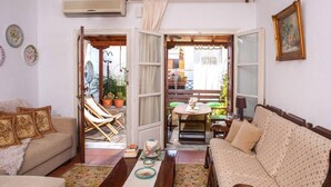 A cozy living room with a sofa, a dining table with chairs, and a small kitchen area. - Harmony Platanidia Pelion (Volos)