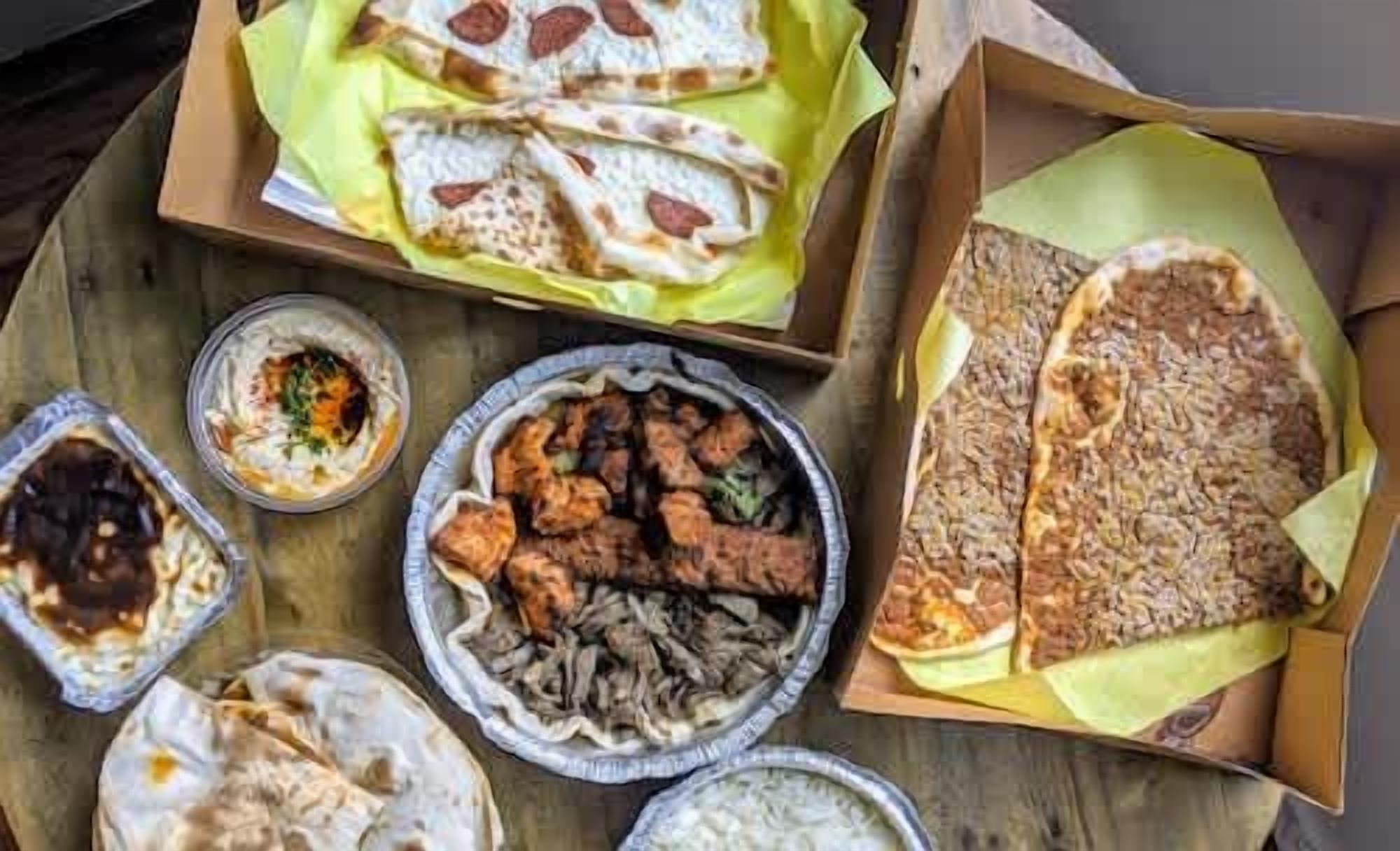 Variedad de alimentos, incluyendo pan plano, un plato de carne y un recipiente pequeño con salsa.