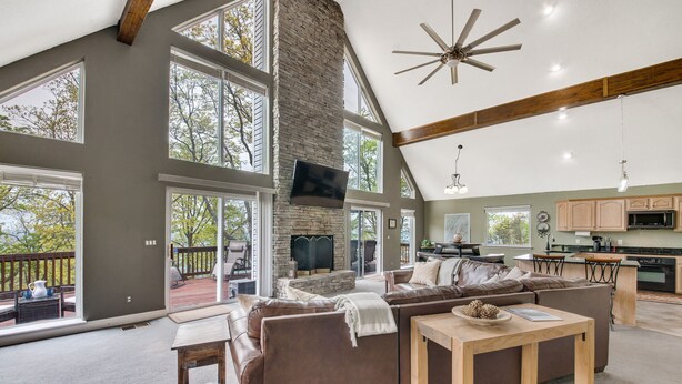 A spacious living area with a large brown leather sectional sofa, a wooden coffee table, and a stone fireplace.