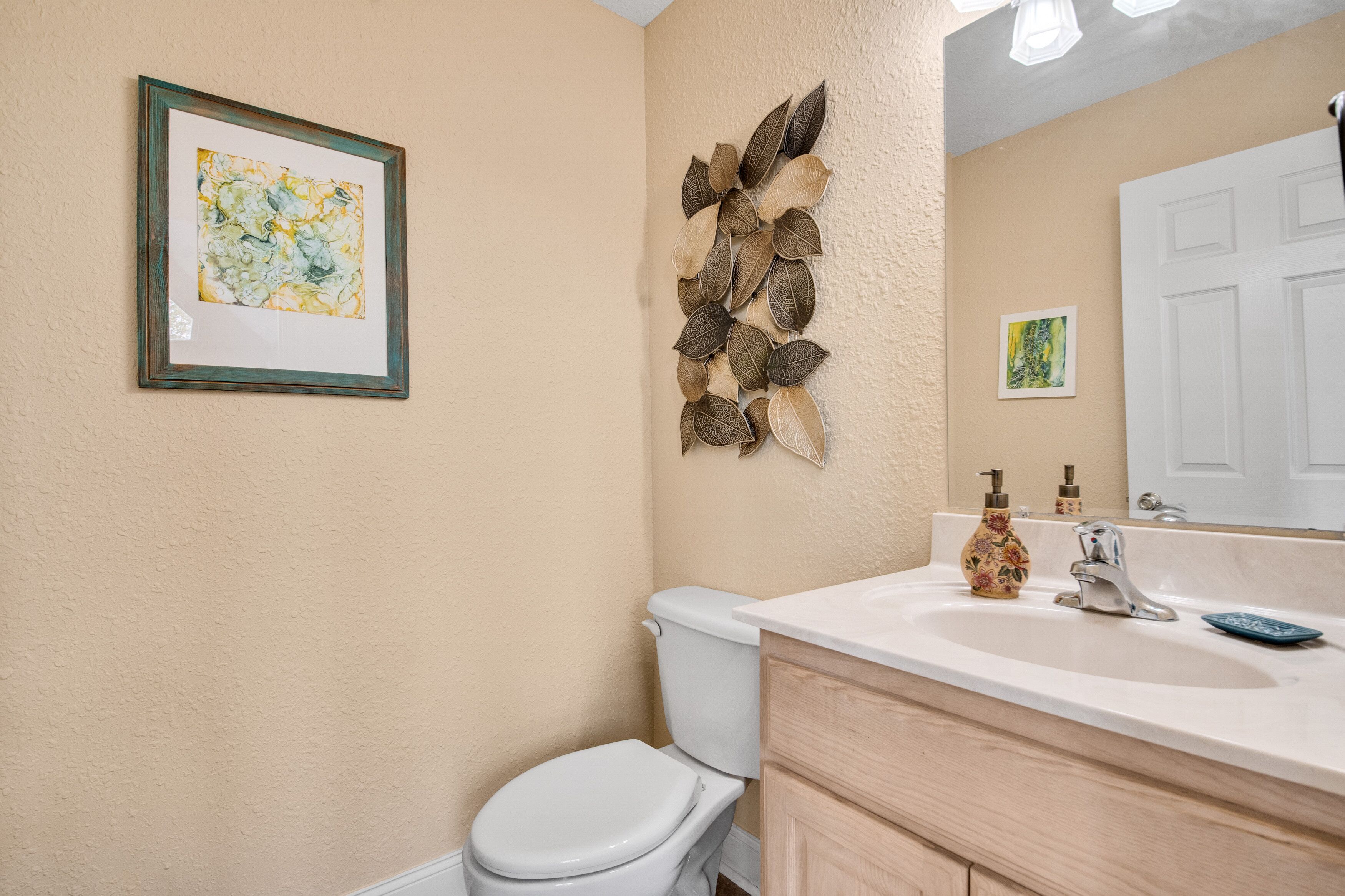 Une salle de bain équipée de toilettes, d’un lavabo et agrémentée d’œuvres d’art décoratives sur les murs.