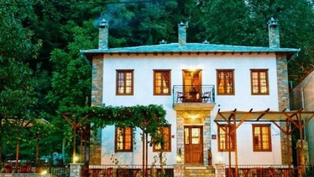 Un edificio a due piani con un ingresso centrale, un balcone e una facciata in pietra.