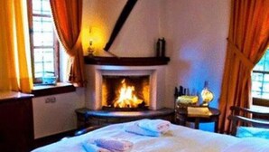 Una camera da letto con camino, un letto con copriletto bianco e pavimento in legno.