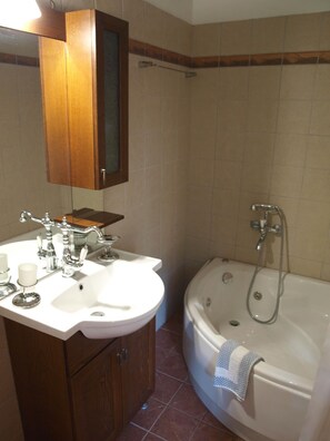 A bathroom with a white sink, a mirror, a wooden cabinet, and a bathtub with a shower head.