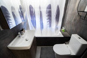 A modern bathroom with a white sink, a bathtub, and a toilet. - Downtown Boutique Flat (Volos)