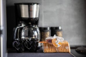 A kitchen with a coffee maker, two black mugs, and a loaf of bread on the counter. - Downtown Boutique Flat (Volos)