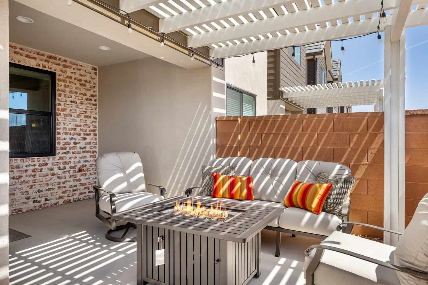 An outdoor patio with a fire feature, seating, and a pergola.