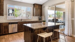 Una cocina moderna con armarios de madera oscura, encimera de granito y una isla grande con taburetes de bar.