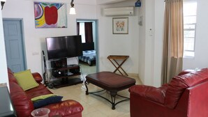 Un salon avec un canapé en cuir rouge, un téléviseur et une petite table en bois.