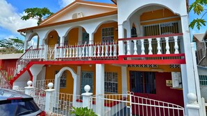 Un bâtiment à deux étages doté d’un balcon, de fenêtres en arc de cercle et d’une façade aux couleurs rouge et blanche.