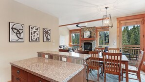 A spacious kitchen with a granite countertop, a stone fireplace, and a dining area with wooden chairs and a table. - Stunning 3 BR Townhome in Keystone! Enjoy the complex hot tub after a long day o (Keystone)