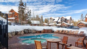 A pool area with lounge chairs and a hot tub, surrounded by snow-covered buildings and trees. - Stunning 3 BR Townhome in Keystone! Enjoy the complex hot tub after a long day o (Keystone)