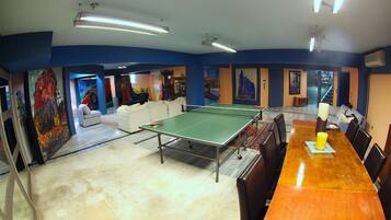 Una habitación con mesa de ping pong, una mesa de comedor de madera y un sofá.