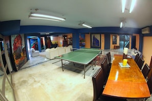 A room with a ping pong table, a wooden dining table, and a sofa. - Eretria Palm Garden Villa (Eretria)